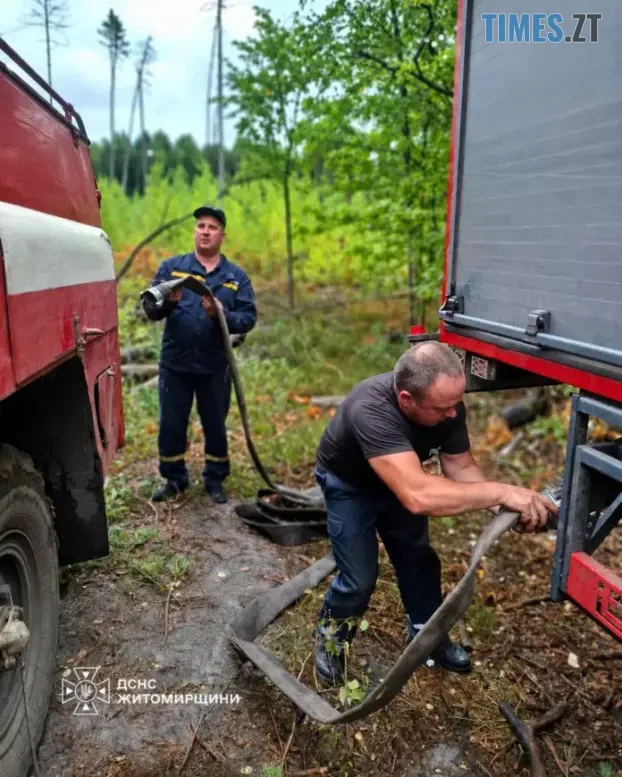 співробітник ДСНС відкручує шланг на пожежній машині