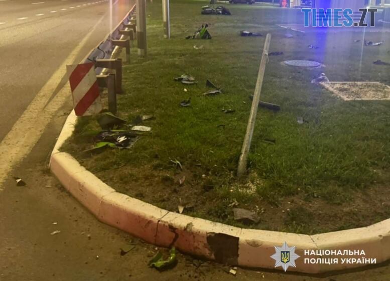 газон на якому розкидані уламки від зіткнення автомобіля та мотоцикла