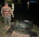 екоінспектор біля річки і поруч лодка та риболовні сітки вилучені з водойми