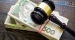 суддівський молоточок лежить на двох пачках гривневих купюр