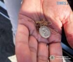 долоня у якій лежать золотий ланцюжок з іконкою та сережки