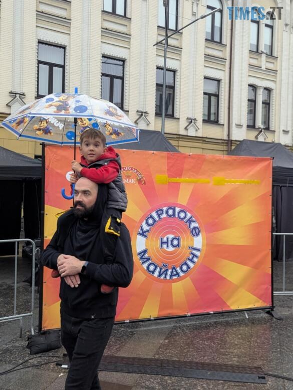 Чоловік з дитиною на плечах та парасолькою