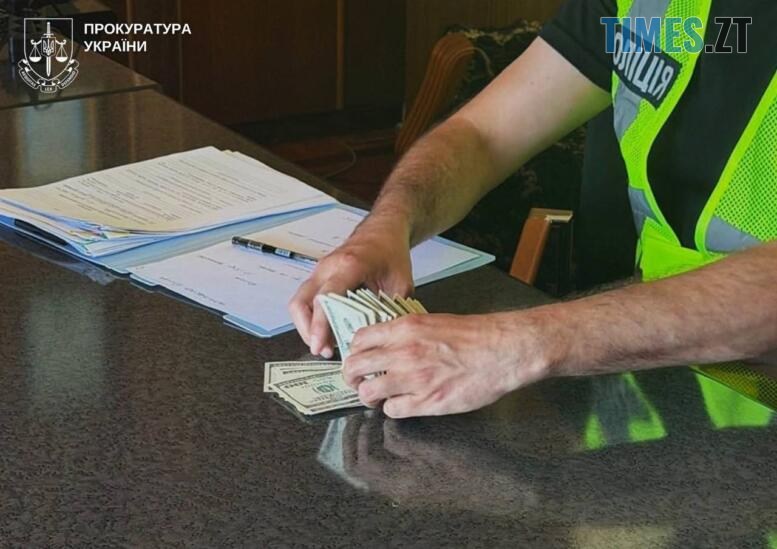 руки правоохоронця тримають пачку вилучених доларів