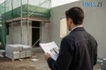 чоловік з паперами та телефоном біля будинку, де проходять будівельні роботи