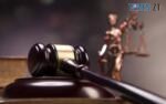 суддівський молоток на фоні фігурки богині Феміди