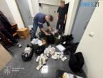 правоохоронець збирає до сумки пачки купюр різних банкнот