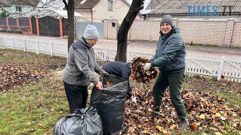 двоє людей прибирають опале пожовкле листя у сквері в Житомирі